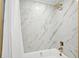This bathroom features a tub with white and marbled-gold tiling and gold fixtures at 205 W Wheeler Rd, Seffner, FL 33584