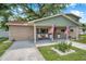 Charming two-story home featuring a covered front porch with rocking chairs and inviting landscaping at 205 W Wheeler Rd, Seffner, FL 33584