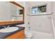 This bathroom has a shower-tub combination with white tile and a wooden vanity with a large mirror at 211 Arlington E Ave, Oldsmar, FL 34677