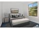 This cozy bedroom has a bright window view, a gray-tone color palette, and a plush bed with decorative pillows at 211 Arlington E Ave, Oldsmar, FL 34677
