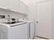 This laundry room features newer-model white appliances and white cabinets for storage at 211 Arlington E Ave, Oldsmar, FL 34677