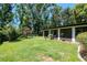 Spacious backyard featuring a covered patio, lush lawn, and mature trees at 23924 Forest Pl, Land O Lakes, FL 34639