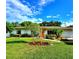 Charming single-story home features a well-manicured lawn, tropical landscaping, and a bright orange front door at 2645 Woodring Dr, Clearwater, FL 33759