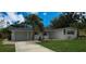 Charming single-story home featuring a driveway, garage, palm trees, and fresh landscaping at 2837 Woodcrest Dr, Sarasota, FL 34239