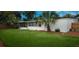 A serene outdoor space with lush grass, mature palm trees, and screened in lanai at 2837 Woodcrest Dr, Sarasota, FL 34239