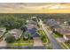 An aerial view of the neighborhood, homes, and surrounding wooded area with lake at sunset at 31646 Baymont Loop, Wesley Chapel, FL 33543