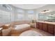 Relaxing bathroom featuring a soaking tub beneath arched windows, vanity with cabinets, and neutral tile flooring at 31646 Baymont Loop, Wesley Chapel, FL 33543
