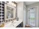 Half bath featuring patterned accent wall, modern mirror and vanity area, and an exterior access door at 31646 Baymont Loop, Wesley Chapel, FL 33543