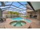 Screened-in pool and spa area featuring brick pavers and lush landscaping at 31646 Baymont Loop, Wesley Chapel, FL 33543
