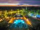 Night aerial view of a community pool surrounded by lounge chairs, a recreation center, and lush landscaping at 31646 Baymont Loop, Wesley Chapel, FL 33543