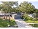 Wide aerial view of a one-story home featuring a gray garage, stone accents, and a well-manicured lawn with a palm tree at 399 Walnut Ct, Palm Harbor, FL 34683