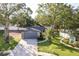 Aerial view of a one-story home featuring a gray garage, stone accents, and a well-manicured lawn with a palm tree at 399 Walnut Ct, Palm Harbor, FL 34683