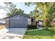 Charming one-story home featuring a gray garage, stone accents and a well-manicured lawn with a vibrant palm tree at 399 Walnut Ct, Palm Harbor, FL 34683