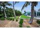An angled view of a landscaped backyard with palm trees and a manicured lawn at 4381 Poinsettia Dr, St Pete Beach, FL 33706