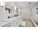 Bathroom featuring double vanity, round mirrors, wood tile flooring, and shower at 4381 Poinsettia Dr, St Pete Beach, FL 33706
