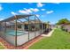 Backyard view of screened in pool with grassy lawn and garden at 4530 Zack Dr, New Port Richey, FL 34653