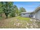 Backyard with grass and trees, showing the back of the house and a fence on the side at 4570 Essex Ln, Spring Hill, FL 34606