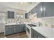 Classic kitchen with gray cabinetry, white countertops and appliances, and a window over the double basin sink at 4570 Essex Ln, Spring Hill, FL 34606