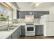 Traditional kitchen featuring gray cabinetry, white appliances, and double basin sink underneath the window at 4570 Essex Ln, Spring Hill, FL 34606