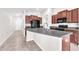 Eat-in kitchen with black appliances, brown cabinets, granite countertops, and grey tile flooring at 4902 Grist Mill Ct, Wimauma, FL 33598