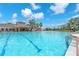 Stunning pool view showcases the community clubhouse, chairs, and lush tropical landscaping at 4902 Grist Mill Ct, Wimauma, FL 33598