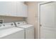 Practical laundry room with white washer, dryer, cabinets, and walls, offering clean and functional space at 5814 Heronpark Pl, Lithia, FL 33547