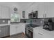 Bright kitchen featuring stainless steel appliances, white cabinetry, and modern gray backsplash at 6602 S Sherrill St, Tampa, FL 33616