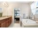 Lovely bathroom with soaking tub, granite counters, and a view into the main bedroom at 6620 Paden Wheel St, Zephyrhills, FL 33541