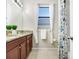 Well-lit bathroom featuring a granite-topped vanity and white curtains flanking a window at 6620 Paden Wheel St, Zephyrhills, FL 33541