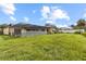 View of the backyard, showing a covered patio, lawn, and partial fencing at 7018 Arbor View Ln, New Port Richey, FL 34653