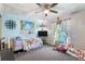 View of a bedroom with carpet flooring, a ceiling fan, and many decorative items and windows at 7018 Arbor View Ln, New Port Richey, FL 34653