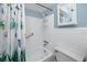 Bright bathroom featuring a tub with shower, white tiling and trim, a small cabinet, and a grab bar for safety at 8584 111Th St # 308, Seminole, FL 33772