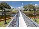 Walkway bridge overlooking a serene pond, connecting to a community clubhouse with a pool in the background at 8584 111Th St # 308, Seminole, FL 33772