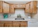 Close-up view of kitchen area featuring stainless steel sink, modern appliances, and natural wood cabinets at 8584 111Th St # 308, Seminole, FL 33772