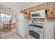 Kitchen area with white appliances, wooden cabinets, and adjacent dining space at 8584 111Th St # 308, Seminole, FL 33772