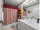 Cozy bathroom with a single sink vanity, and a red and white striped shower curtain at 8731 Huntfield St, Tampa, FL 33635