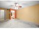 A bedroom with a ceiling fan and light, orange accent wall, and access to the bathroom at 8731 Huntfield St, Tampa, FL 33635