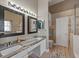 Modern bathroom featuring a double vanity with granite countertops, white cabinetry, and a separate shower area at 9702 Mary Robin Dr, Riverview, FL 33569