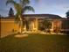 Beautiful single-story home featuring a well-manicured lawn and landscaping in the evening at 9702 Mary Robin Dr, Riverview, FL 33569