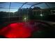 A screened-in pool glows in red at twilight, a relaxing oasis for evening swims and outdoor enjoyment at 9702 Mary Robin Dr, Riverview, FL 33569