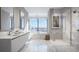 Modern bathroom with dual sinks, marble countertops, glass shower, and a soaking tub with a city view at 111 S Ashley Dr # 3308, Tampa, FL 33602