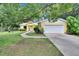 Charming yellow home featuring a white garage door, stone accents, and lush landscaping at 1110 Mercer Loop, Plant City, FL 33567