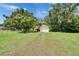 Spacious front yard featuring mature trees and a view of the charming yellow home at 1110 Mercer Loop, Plant City, FL 33567