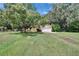 Inviting front yard with lush lawn, mature trees, and charming yellow home at 1110 Mercer Loop, Plant City, FL 33567