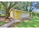 Exterior view of the detached garage showing the white doors, yellow siding, and concrete pathway at 1110 Mercer Loop, Plant City, FL 33567