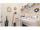 Bright laundry room with stacked white washer and dryer, white walls, and a wire rack with cleaning supplies at 12017 Gillingham Harbor Ln, Gibsonton, FL 33534