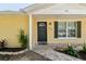 Close-up of a yellow home featuring a decorative front door, new landscaping, and paved walkway at 1320 Oak Valley Dr, Seffner, FL 33584
