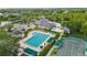 Aerial view of a community pool, tennis courts, and clubhouse surrounded by lush landscaping and a parking area at 18004 Avalon Ln, Tampa, FL 33647