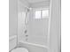Well-lit bathroom featuring a standard tub with shower, white tile surround, and standard toilet at 18004 Avalon Ln, Tampa, FL 33647