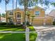 Charming two-story home featuring a red double-door entry, three-car garage, and neatly landscaped front yard at 18004 Avalon Ln, Tampa, FL 33647
